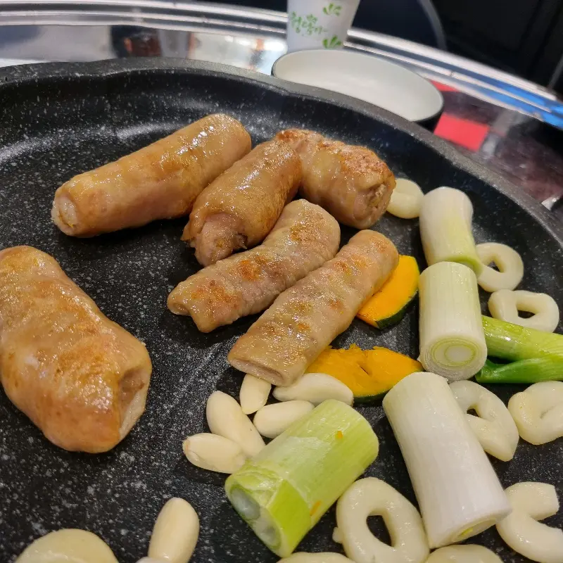 불판 위에서 구워지는 막창, 떡, 호박, 대파