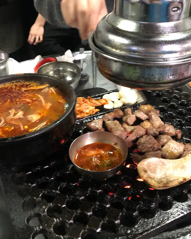 연탄불 위에 올려진 청국장 뚝배기와 고기, 김치
