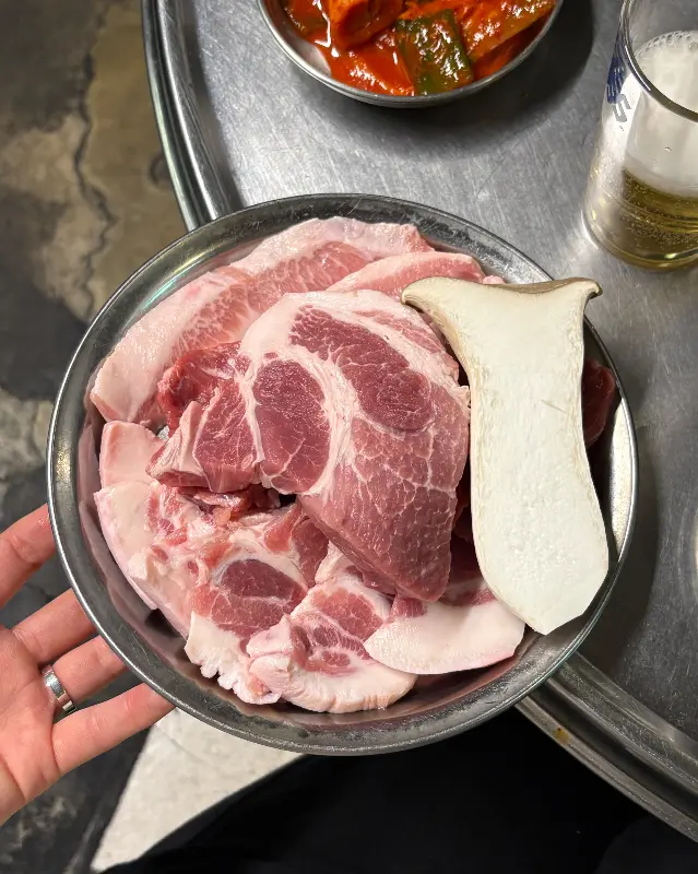 접시에 담겨 나온 신선한 돼지고기와 팽이버섯