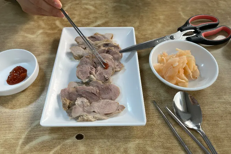 수육에 양념장을 올려 먹는 모습