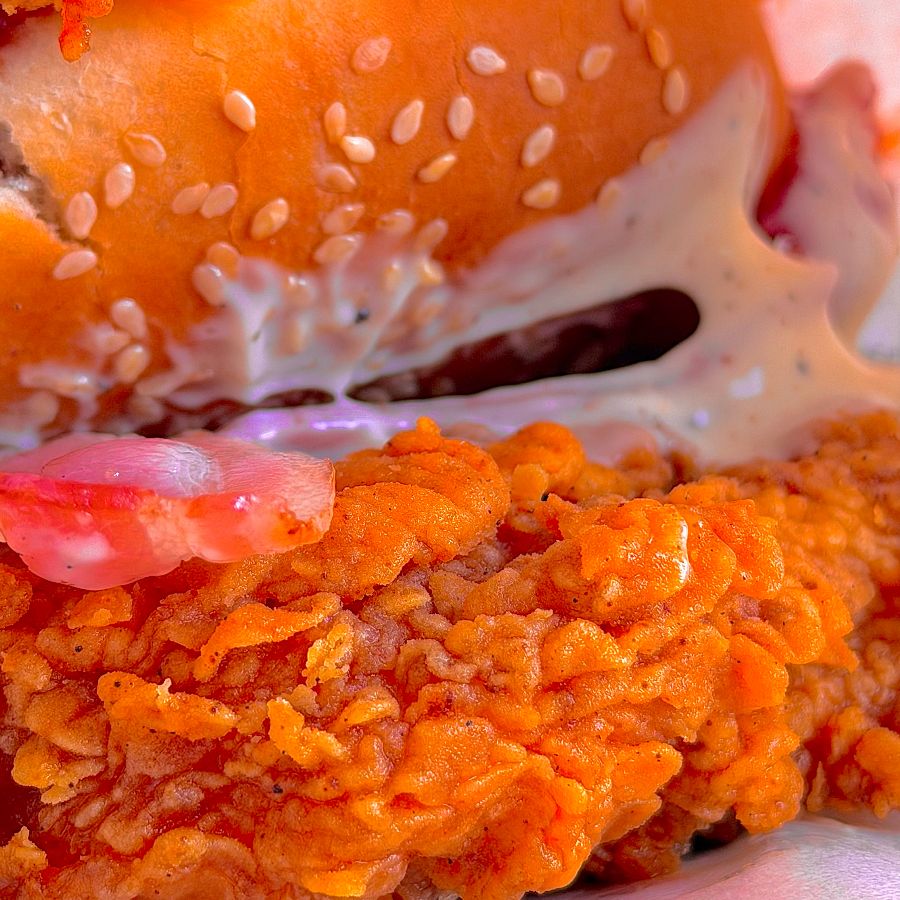 업사이드 다운 징거 버거의 단면을 클로즈업한 사진. 바삭한 치킨 패티와 해쉬브라운이 보인다.