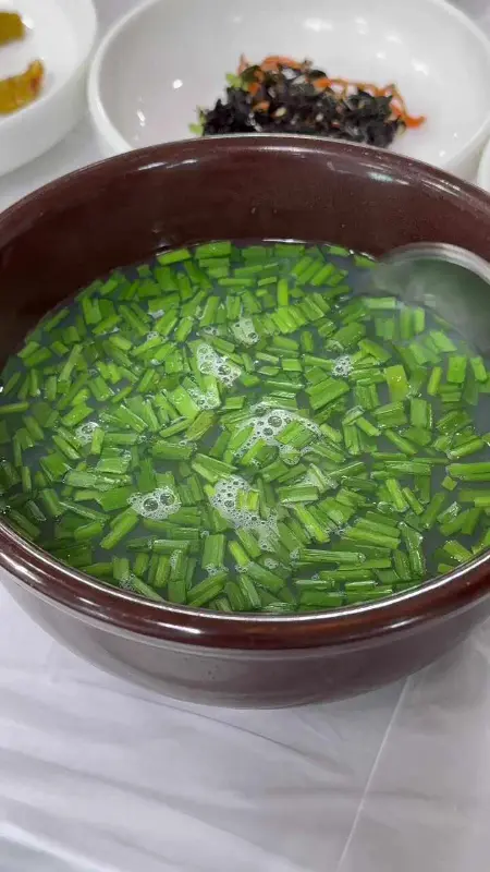 재첩국에 부추가 가득 담겨 있는 모습