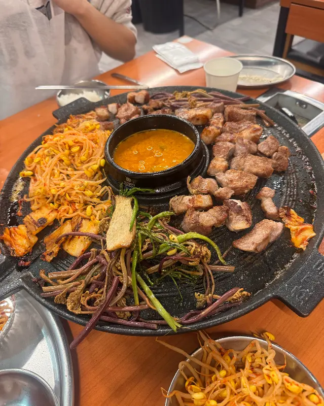 솥뚜껑에 푸짐하게 올려진 삼겹살과 각종 채소들