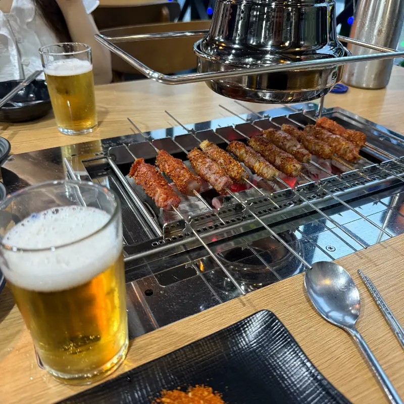 숯불에 노릇하게 익어가는 양꼬치와 시원한 맥주 한 잔