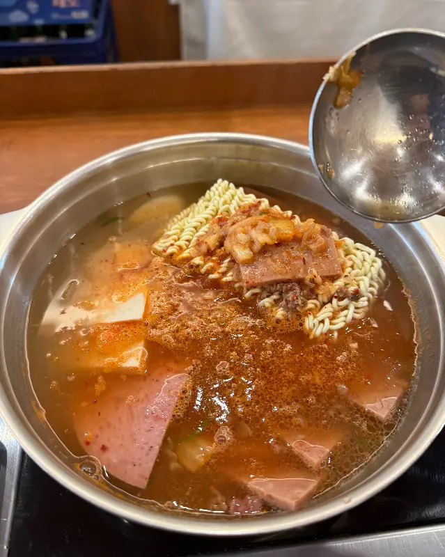 국자로 부대찌개를 뜨는 모습