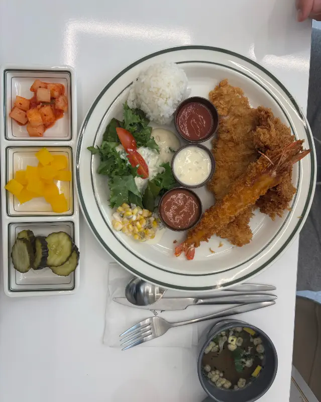 돈까스와 새우튀김, 샐러드, 밥, 소스, 스프 등이 한 상 차림으로 제공되는 모습