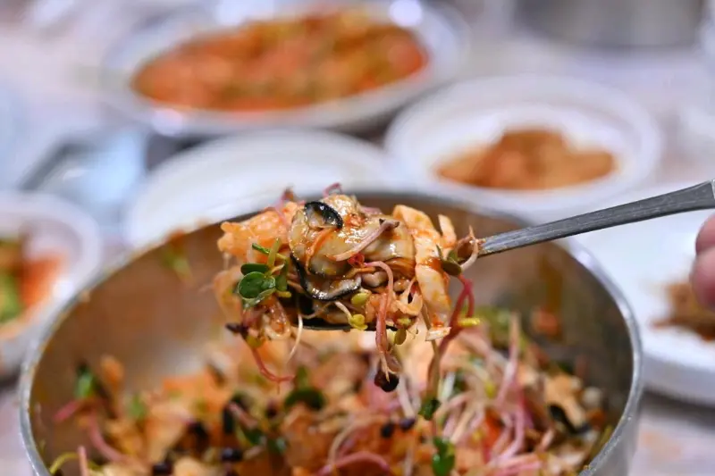 멍게비빔밥을 수저로 들어올리는 모습