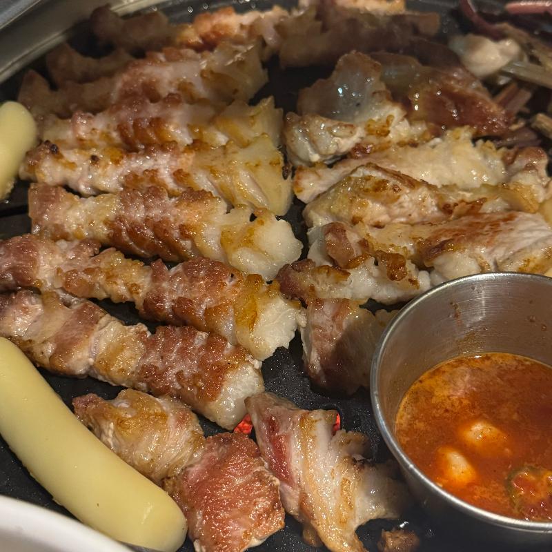 불판 위에서 맛있게 구워지는 삼겹살과 멜젓
