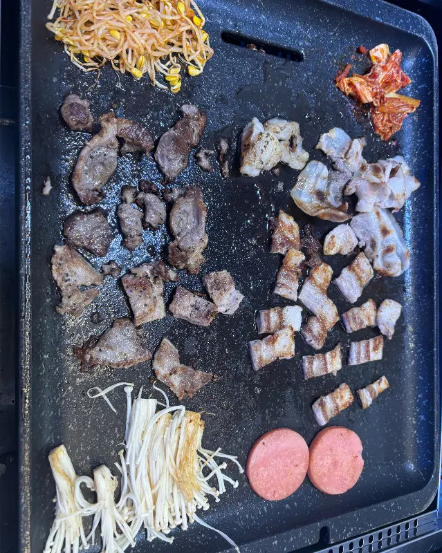 삼겹살, 목살, 김치, 콩나물 등이 함께 구워지고 있는 불판