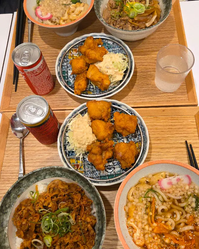 테이블 위에 다양한 메뉴가 놓여져 있다. 가라아게, 규동, 우동 등 푸짐한 한 상 차림