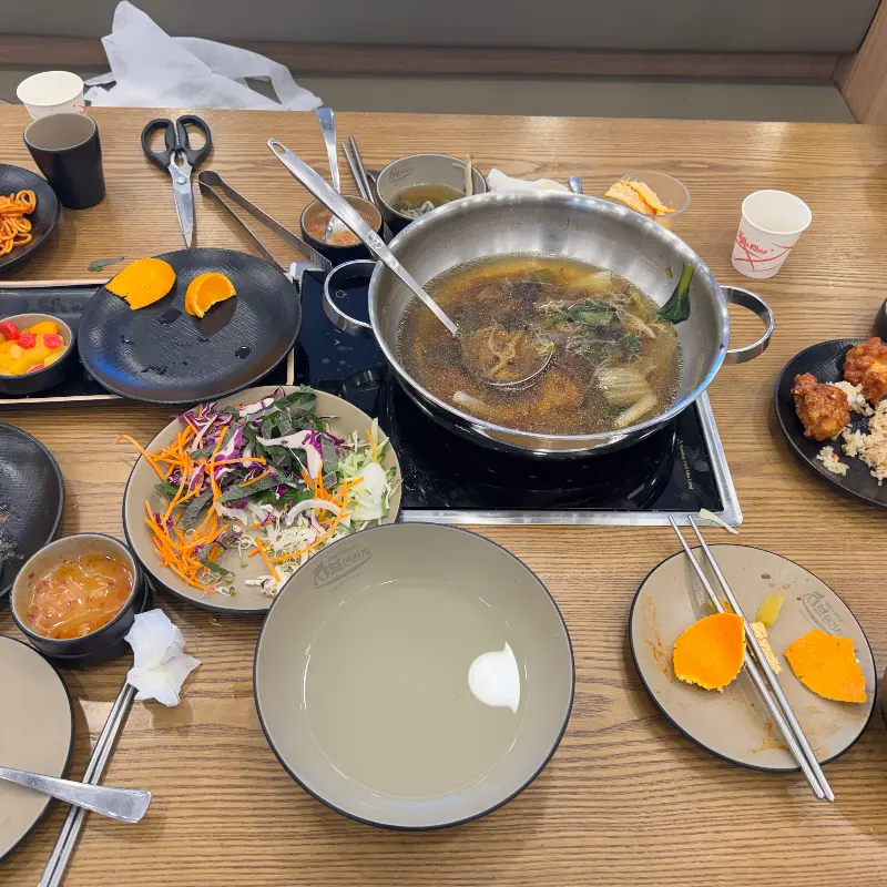 테이블 위에 놓인 샤브샤브 냄비와 다양한 음식들