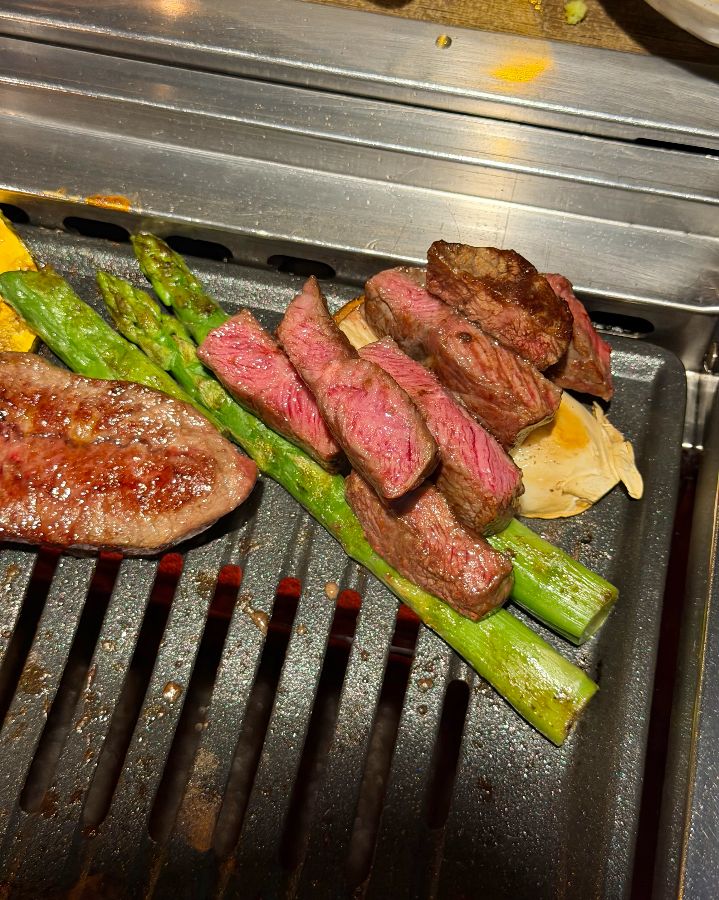 숯불 위에서 맛있게 익어가는 소고기와 아스파라거스. 육즙이 촉촉하게 배어 나오는 모습이 식욕을 자극한다.