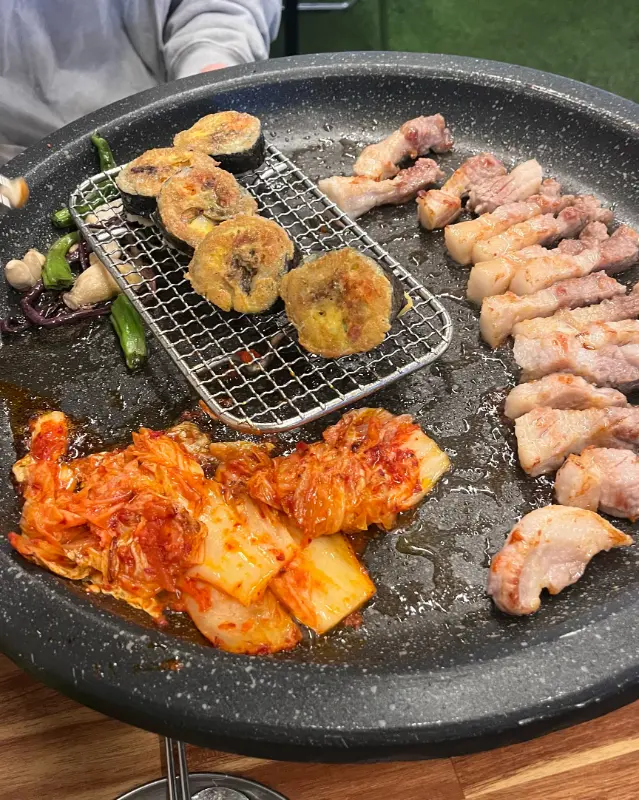 불판 위에서 익어가는 삼겹살과 김치