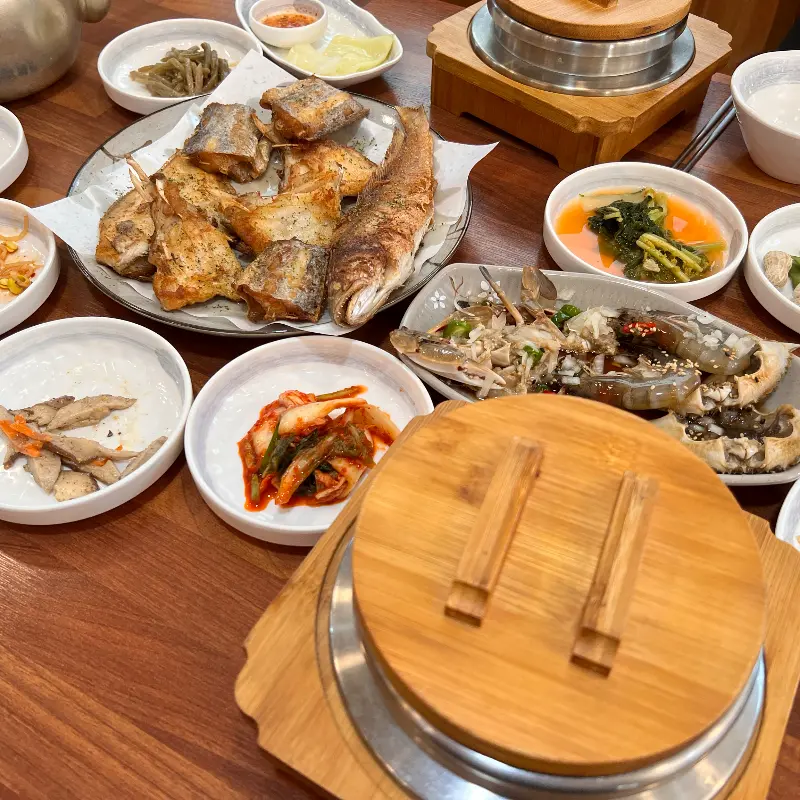 다채로운 밑반찬과 솥밥, 생선구이, 간장게장이 차려진 푸짐한 한 상 차림