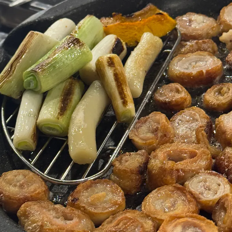 막창, 대파, 떡, 호박이 함께 구워지고 있는 모습