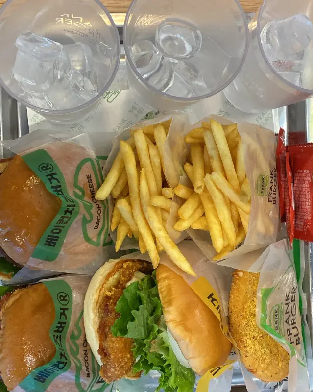 쟁반 위에 놓인 프랭크 버거와 치즈 버거, 감자튀김, 치킨