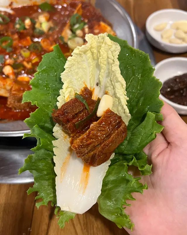 싱싱한 쌈 채소에 찜소갈비를 싸서 먹는 모습