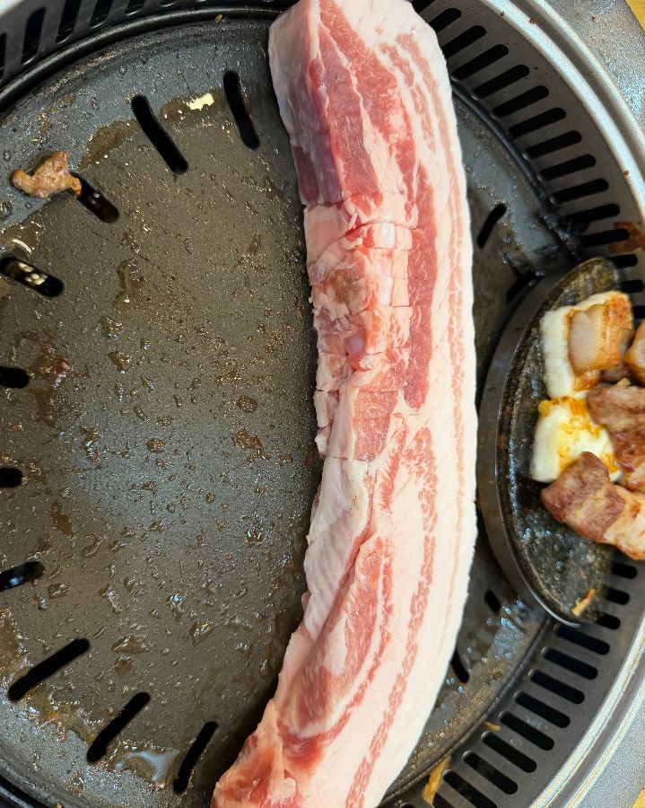 맛찬들 왕소금구이 과천점의 삼겹살이 불판 위에서 구워지는 모습