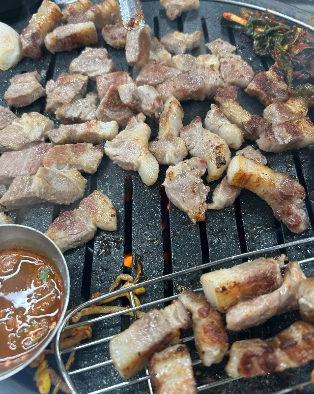 잘 구워진 삼겹살이 불판 위에 놓여 있는 모습