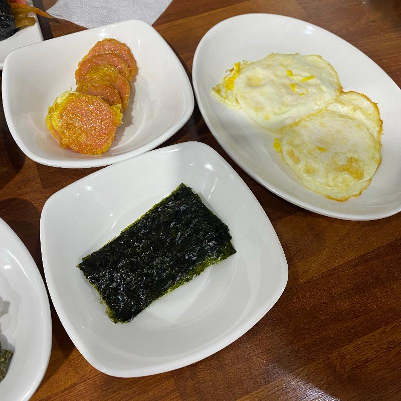 계란후라이, 분홍 소세지, 김이 담긴 밑반찬 접시