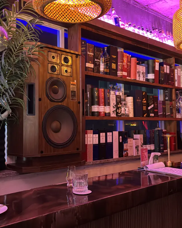 바 테이블 뒤로 보이는 거대한 스피커와 술병들