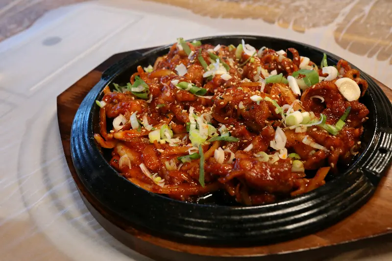 매콤한 양념에 버무려진 닭발 위에 파와 깨가 뿌려져 있는 사진