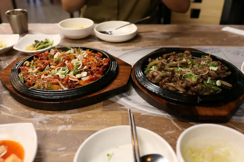 오삼불고기와 소불고기가 철판 위에 담겨 테이블에 놓여 있는 사진