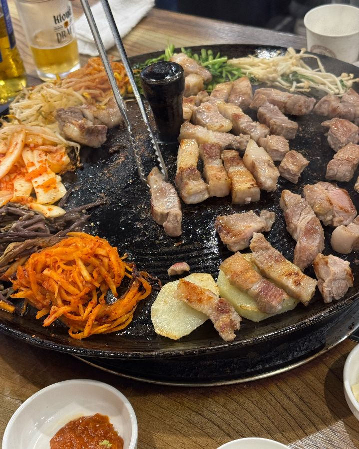 노릇하게 구워진 삼겹살을 집게로 들어 올리는 모습