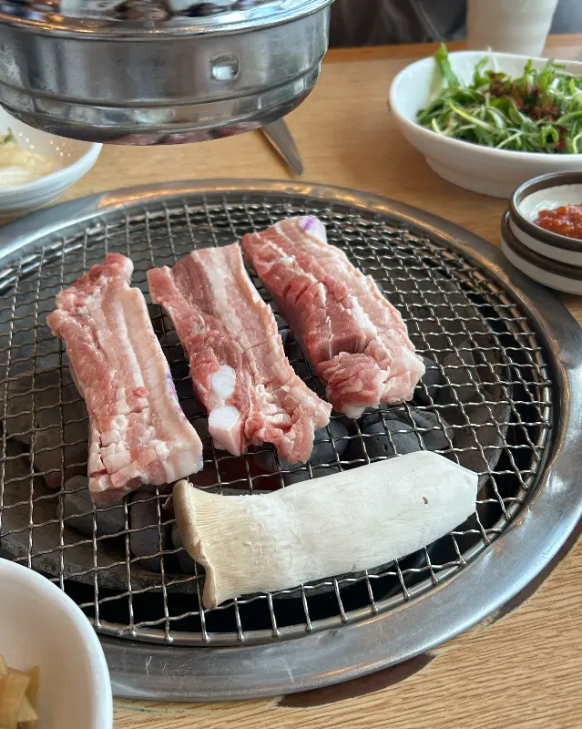 불판 위에서 익어가는 흑돼지 오겹살과 새송이버섯