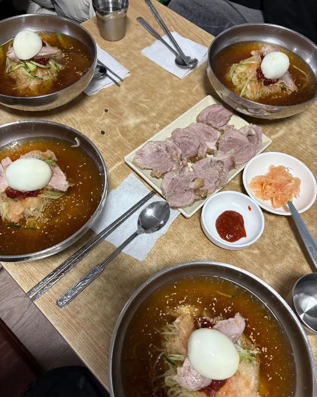 여러 그릇의 밀면과 수육이 놓인 테이블