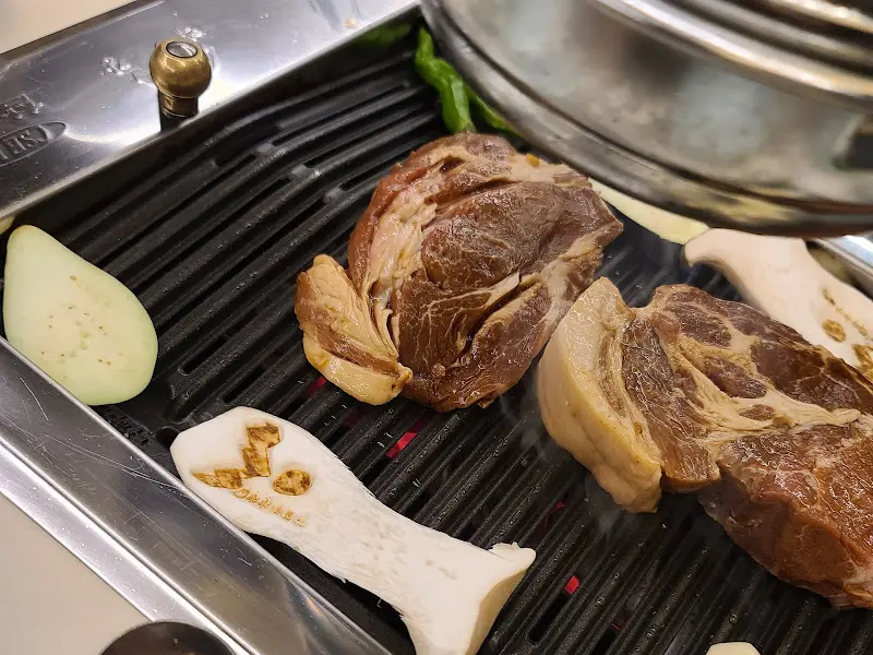 불판 위에서 구워지는 목살과 버섯