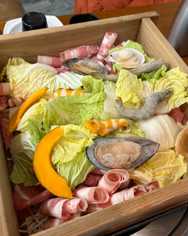 편백찜의 푸짐한 비주얼. 신선한 해산물과 야채가 가득 담겨 있다.