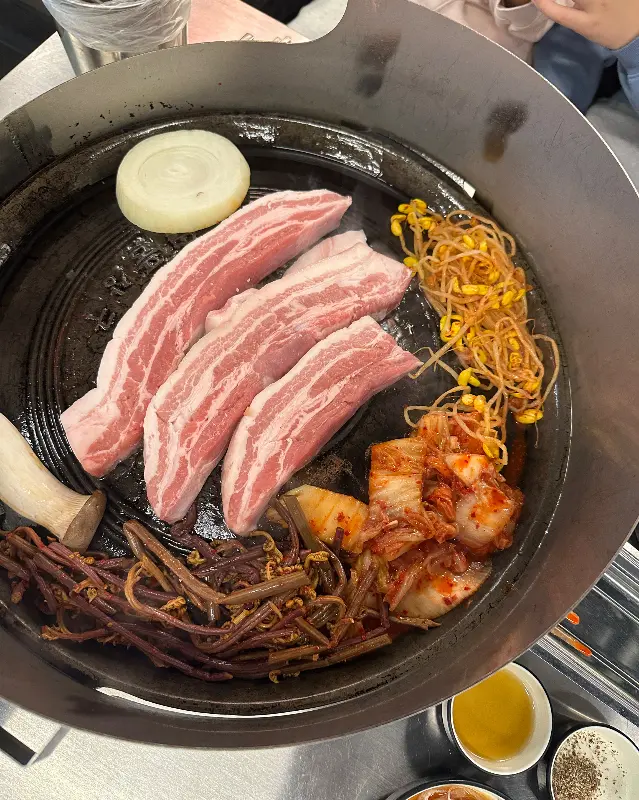 솥뚜껑에 구워지는 삼겹살과 채소