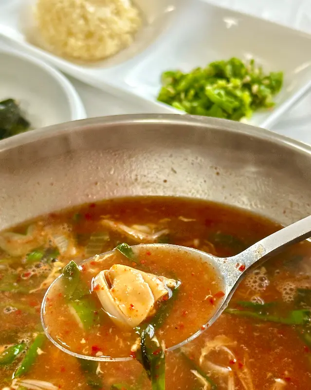 숟가락 위에 섭과 부추를 함께 올려 국물을 떠먹는 모습. 섭의 쫄깃함과 부추의 아삭함이 느껴진다.