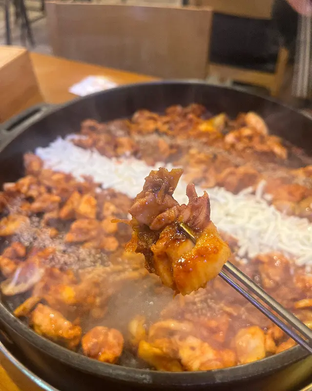 젓가락으로 닭갈비를 집어 올리는 모습