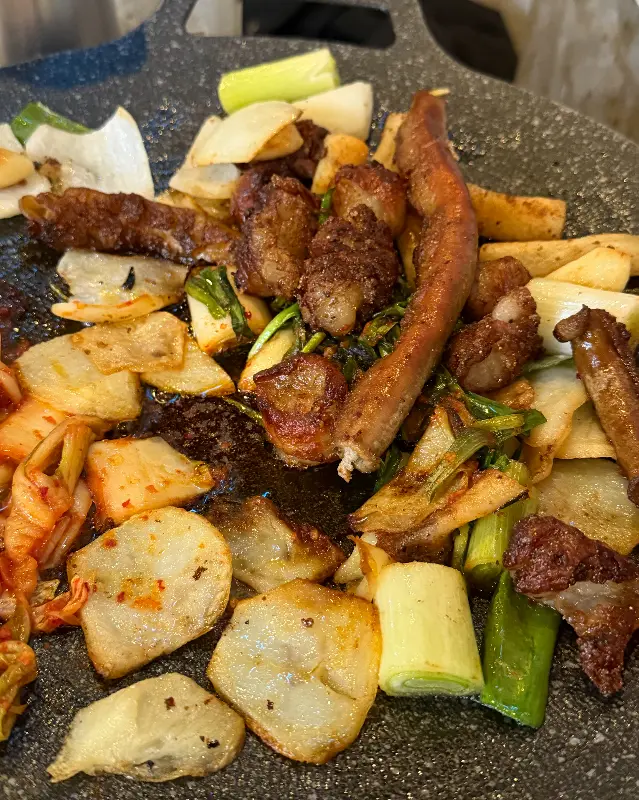 잘 구워진 곱창과 야채들이 철판 위에 놓여 있는 모습