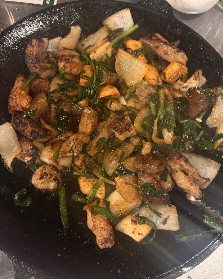 돌판 위에 곱창, 양파, 감자, 부추가 맛있게 구워진 모습