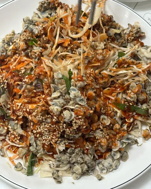 젓가락으로 재첩회무침을 집어 올리는 모습