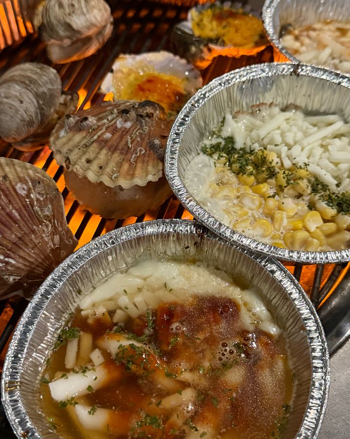 불판 위에서 익어가는 조개와 곁들임 메뉴