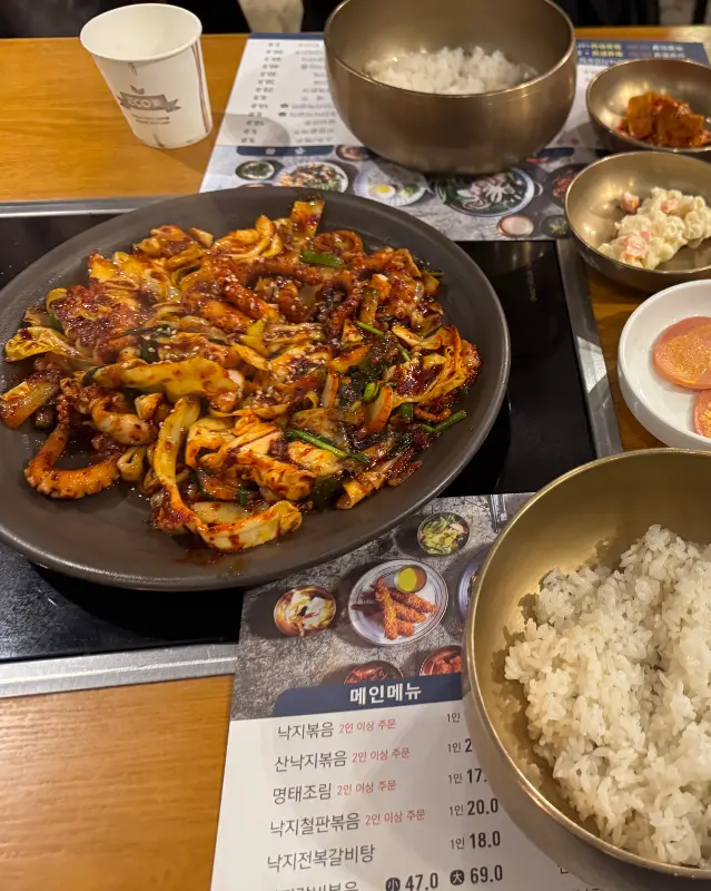 낙지볶음과 밥, 다양한 반찬들이 테이블 위에 놓여 있는 모습