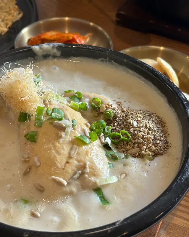 테이블 위에 놓인 흑임자 삼계탕과 반찬