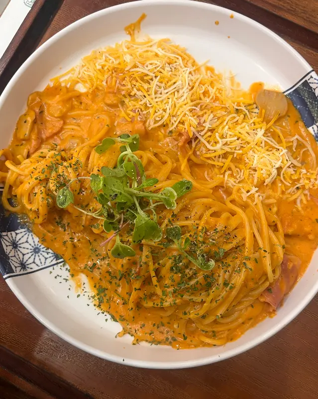 로제 파스타 위에 치즈와 채소가 올려져 있다.