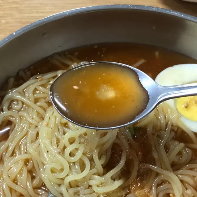 물밀면 육수를 숟가락으로 떠먹는 모습
