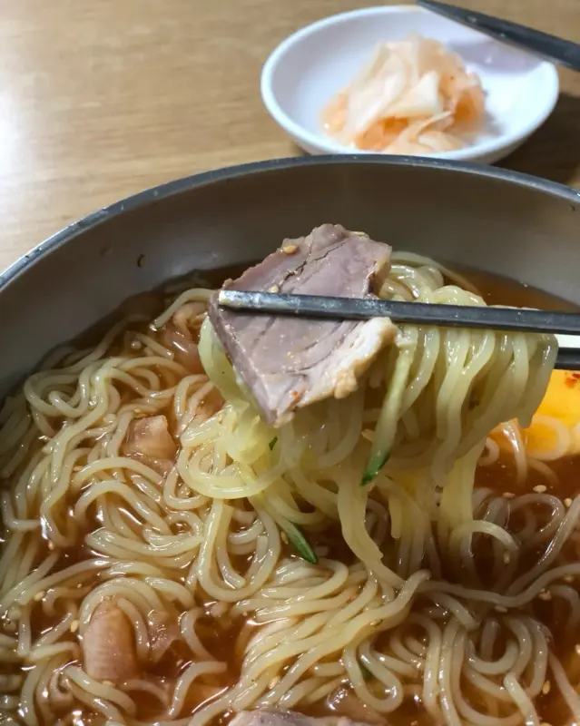 젓가락으로 밀면 면발과 수육을 함께 들어올린 모습