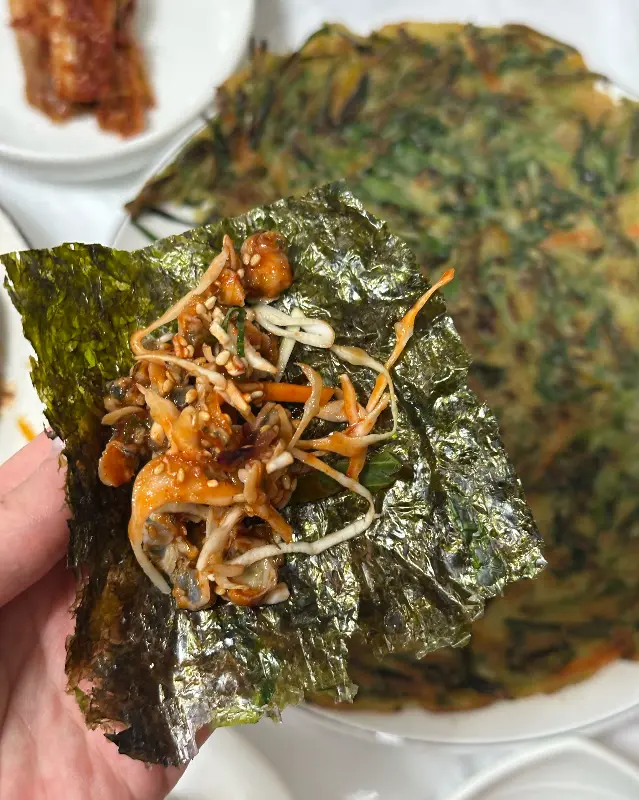 김에 재첩회무침을 싸서 먹는 모습