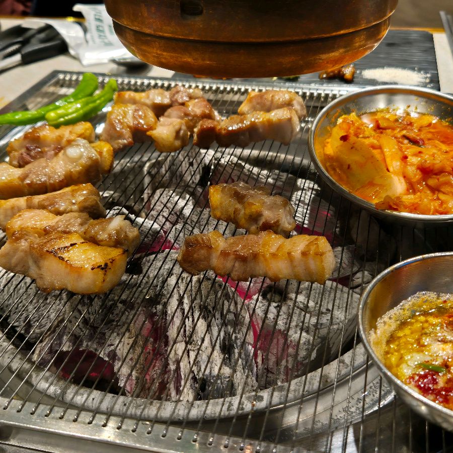 숯불 위에서 노릇하게 익어가는 두툼한 삼겹살