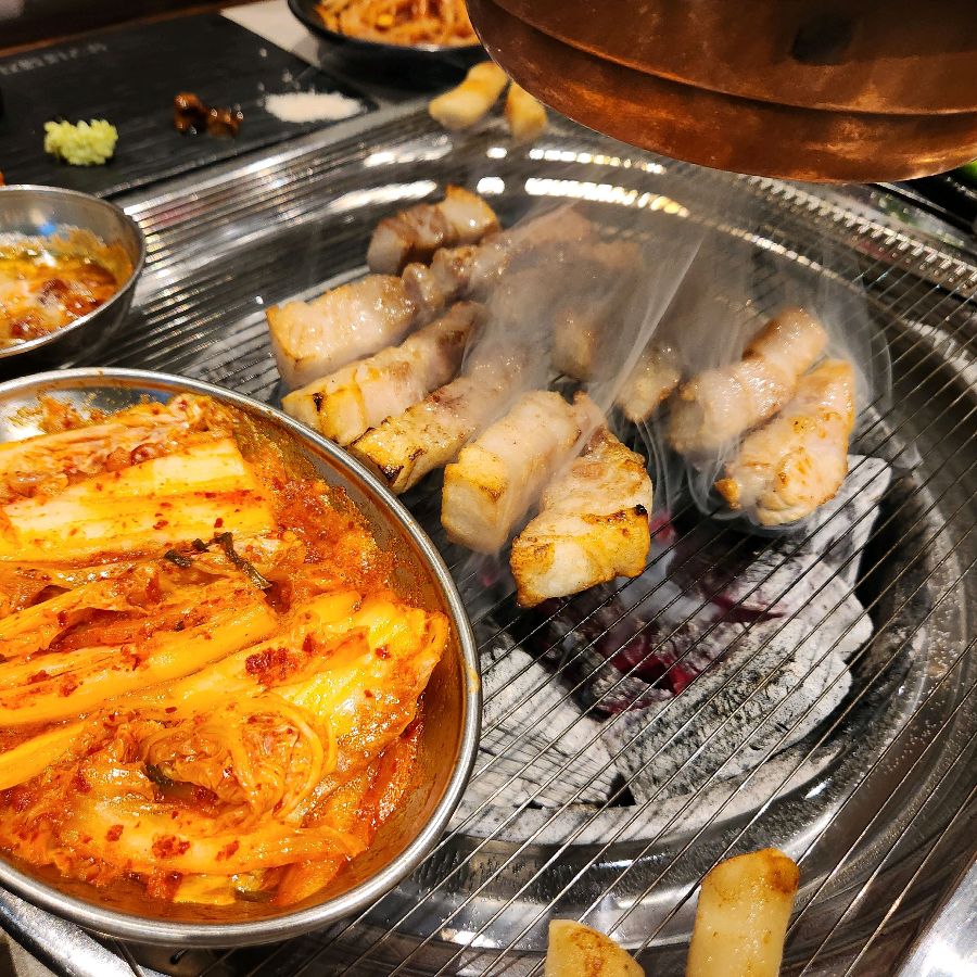 육즙이 풍부한 삼겹살이 숯불 향을 머금고 맛있게 익어가는 모습