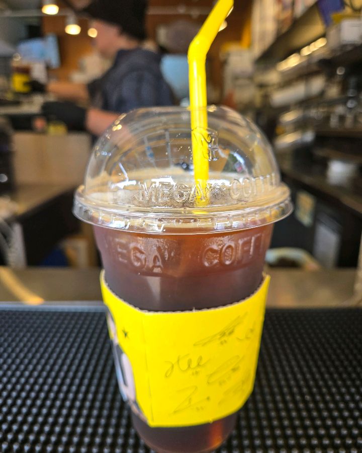 노란색 스트로우가 꽂힌 아이스 아메리카노