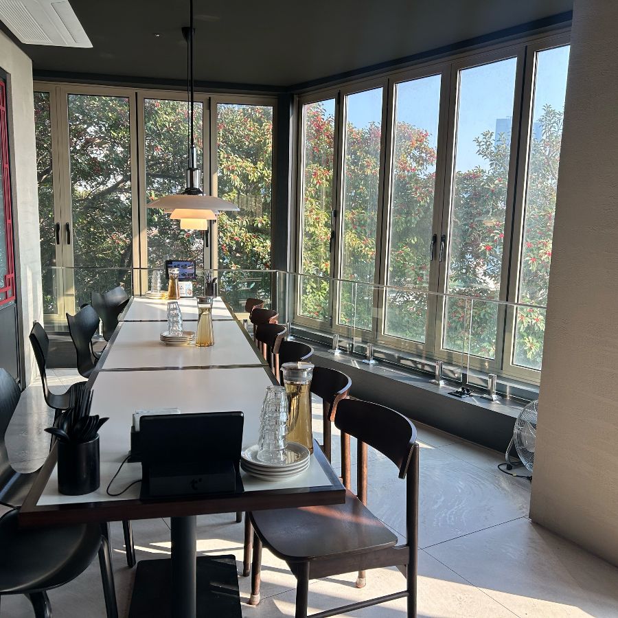 통창으로 햇살이 가득 들어오는 룸 공간, 테이블이 길게 놓여 있어 단체 모임에 적합해 보인다.