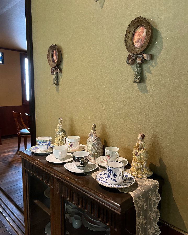 앤티크 장식장 위에 놓인 예쁜 찻잔 세트와 인형